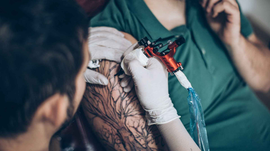 A tattoo artist creates a tattoo