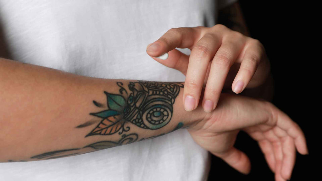 Woman rubbing lotion on her tattoo