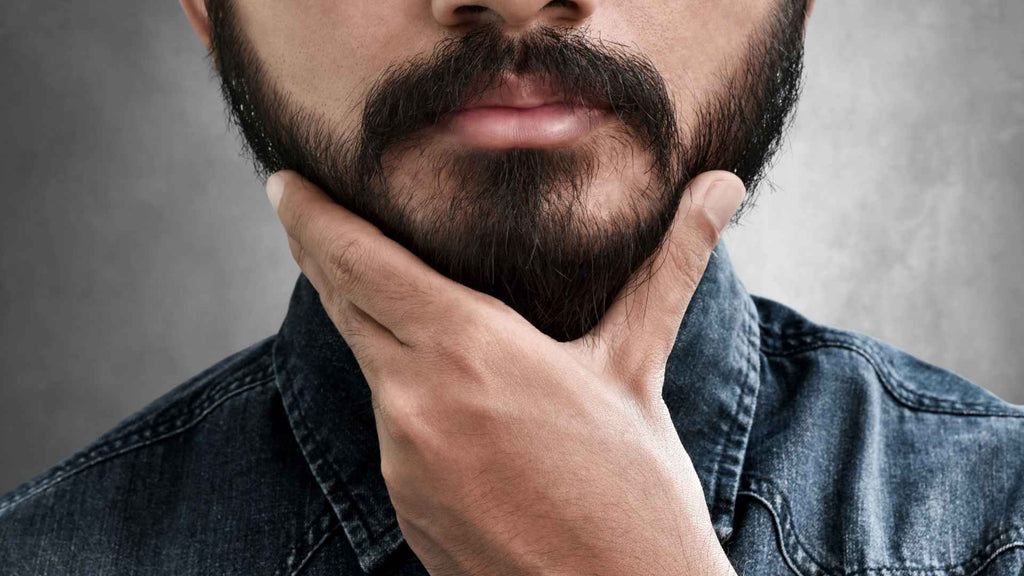 A man with a beard is putting his hand on his chin.