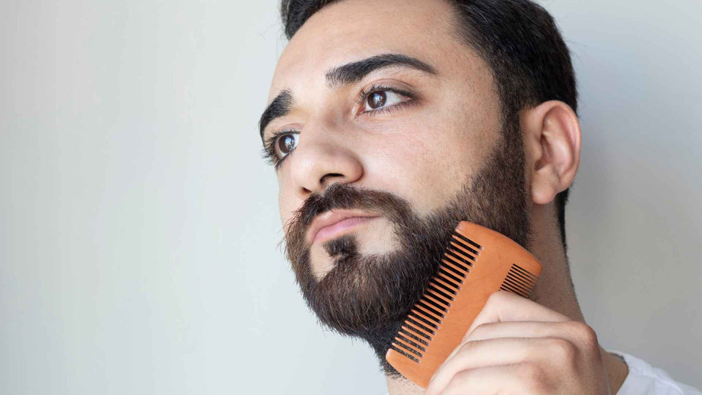 A man is brushing his beard with a comb.