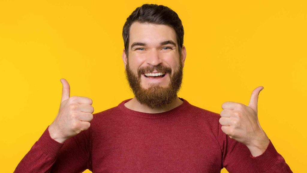 A man with a beard showing thumbs up on a yellow background.
