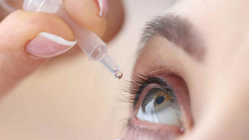 A woman's eye experiencing eyelid pruritus and being administered eye drops.