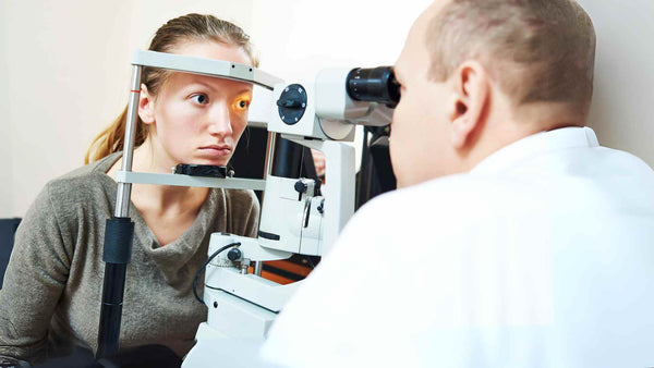 Una mujer está teniendo los ojos examinados por un optometrista.