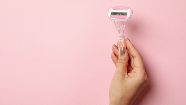 A woman's hand holding a pink shaver to address not pressing too hard whileshaving.