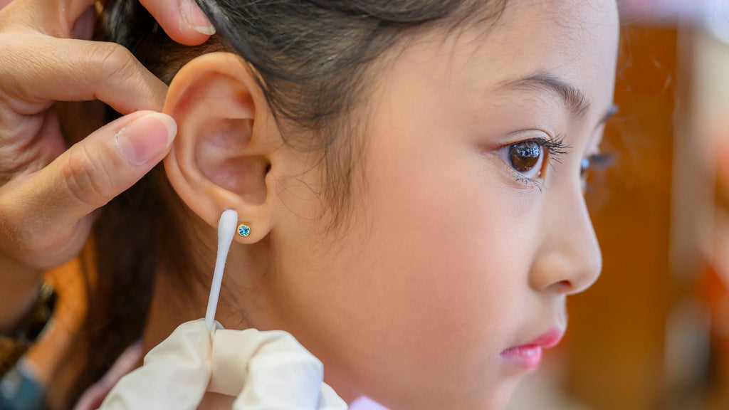 A young girl is getting her ear piercing cleaned.