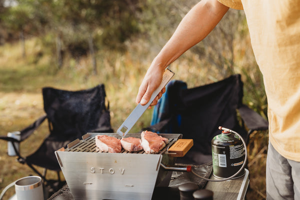 The STOV BBQ tongs in use, flipping burgers.