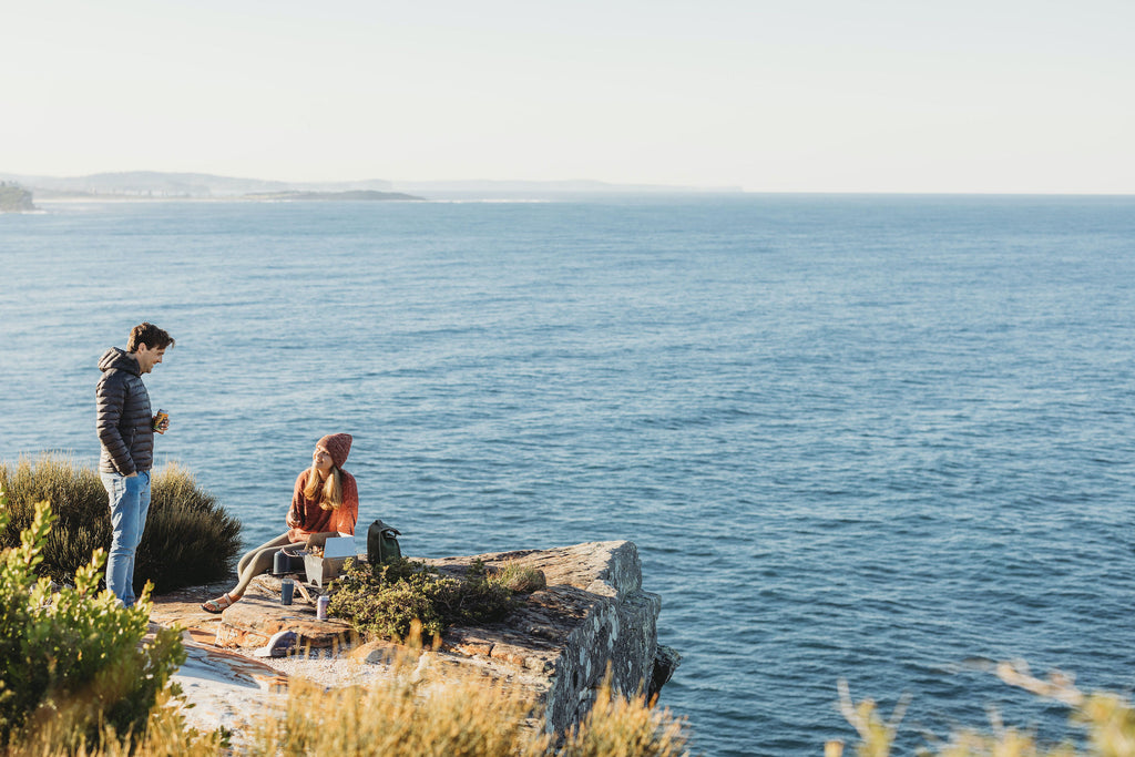 The best portable bbq set up on a clifftop overlooking the ocean. The stov bbq is grilling while two people chat