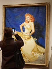 a visitor admires and takes a photo of the McClelland Barclay portrait of Anna Neagle at the National Gallery, London, England, 2023. Photo ©K. Mogg