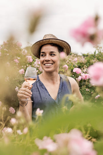 Жена с вино розе в поле с рози от сорта роза дамасцена за българско розово масло