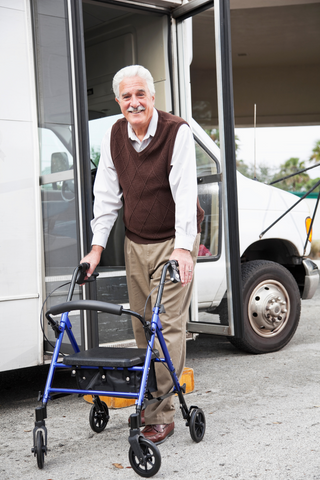 Elderly gentleman standing in front of a shuttle bus with his walker