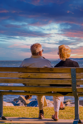 Elderly couple on a bench enjoying the sunset