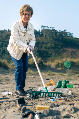 Elderly woman raking garbage