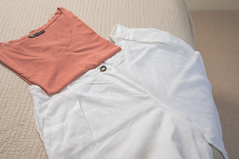 white linen trousers laid out on a bed with a rust colored tee