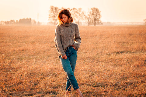 a woman wearing blue denim pants standing in a field