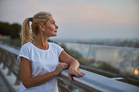 an attractive woman wearing a white t-shirt, watching the sun setting