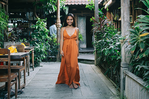a beautiful woman wearing a stunning silk rust colored strappy maxi dress