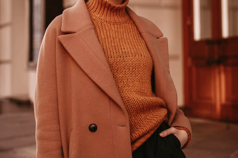 a rust colored woolen coat worn over a roll neck sweater