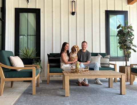 Husband, Wife, and Dog Sitting on Outmore Living's Heated Outdoor Furniture in a covered outdoor living area