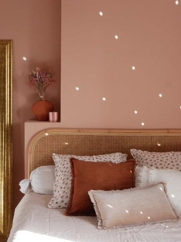 Mur rose ocre derrière un lit avec tête de lit en bois