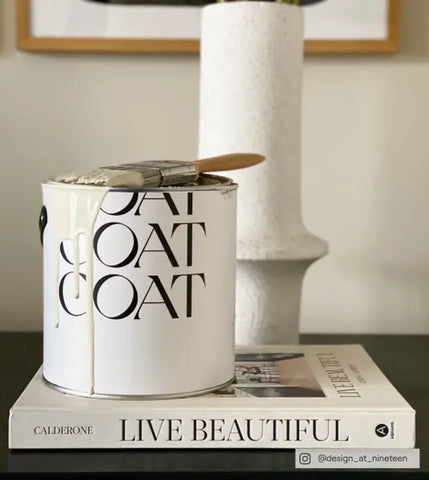 Pot de peinture COAT posé sur un livre nommé « live beautiful »