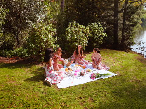 A women's picnic surrounded by a forest and a lake