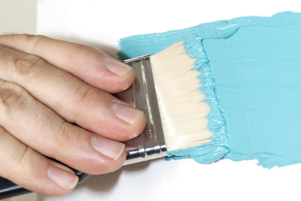 Hand dragging large brush through aqua paint.