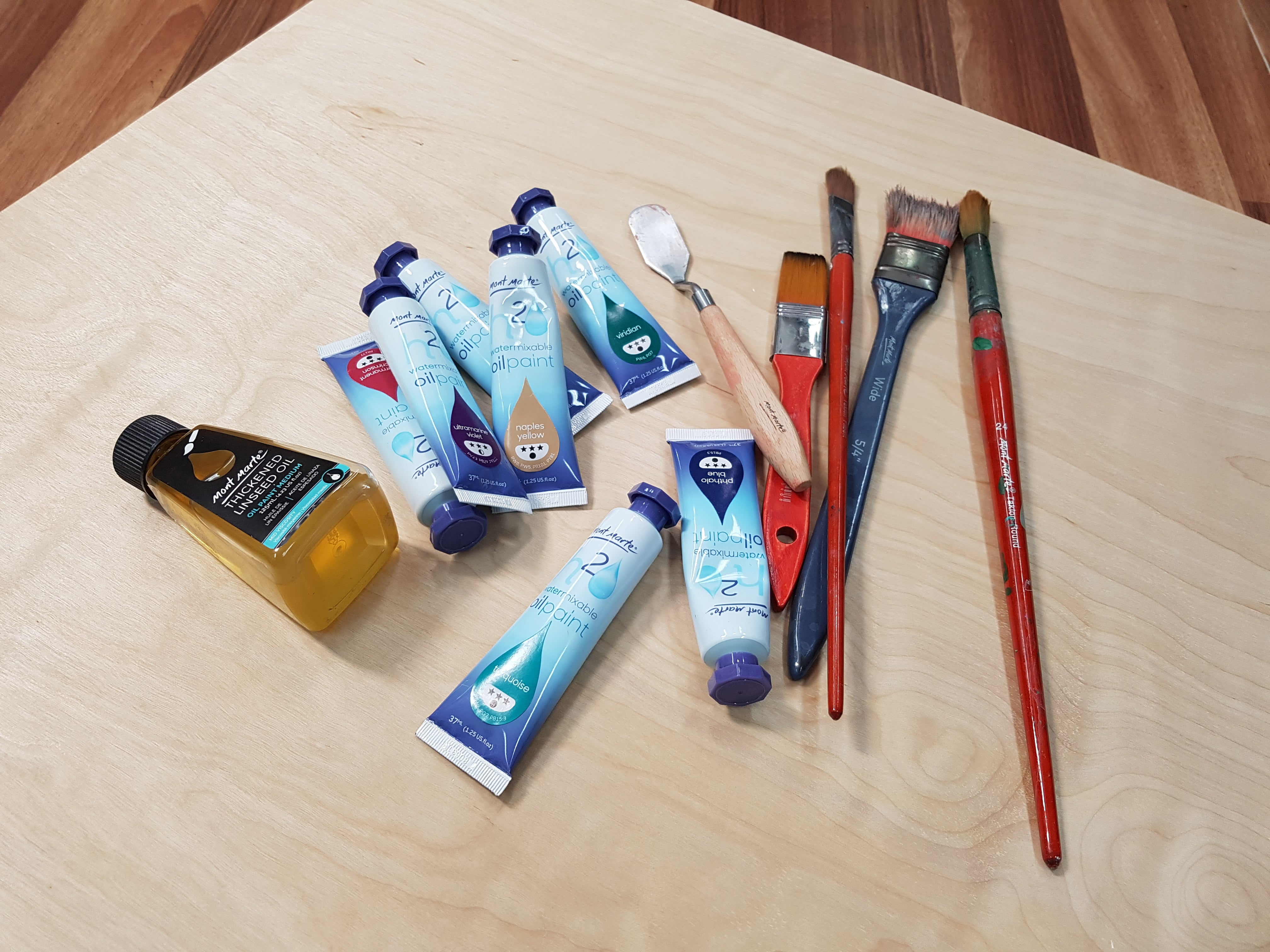 Pile of painting supplies on a timber desk.