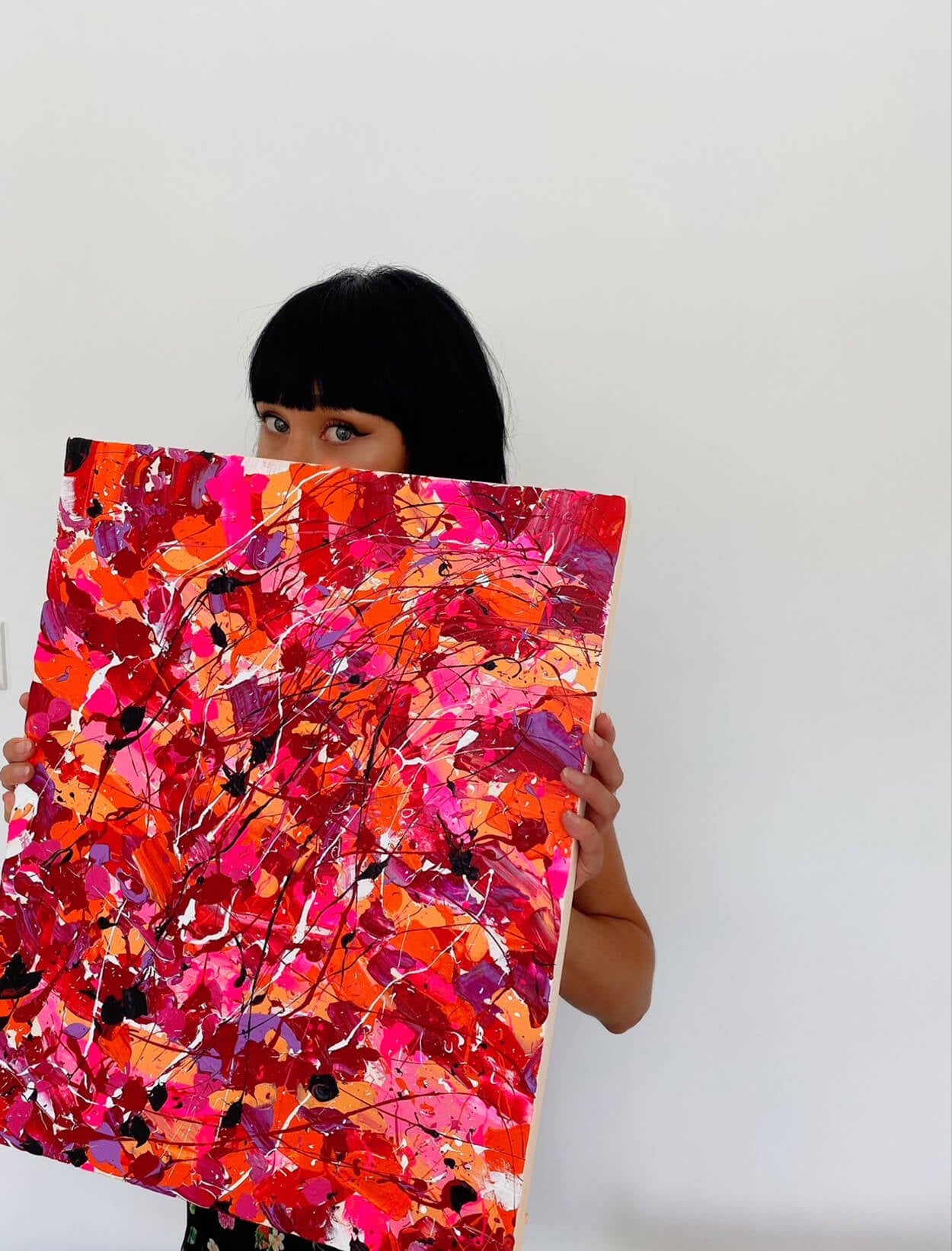 Artist Bridget Bradley holding a red abstract artwork in front of her