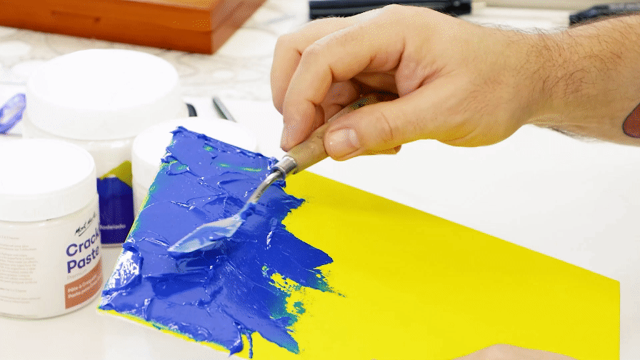 1. Blue acrylic paint mixed with Impasto being applied to a yellow canvas