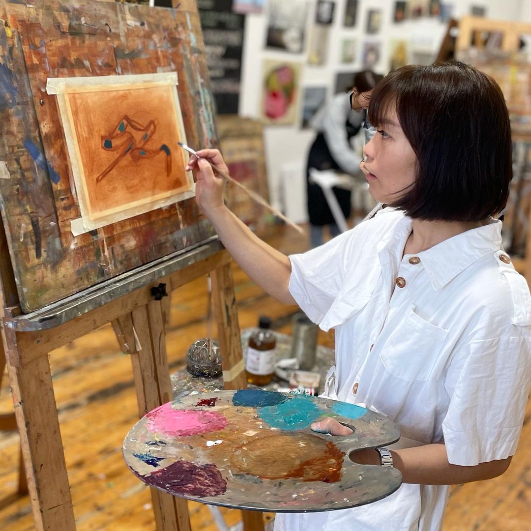 1. Candy painting on an easel wearing a white jumpsuit