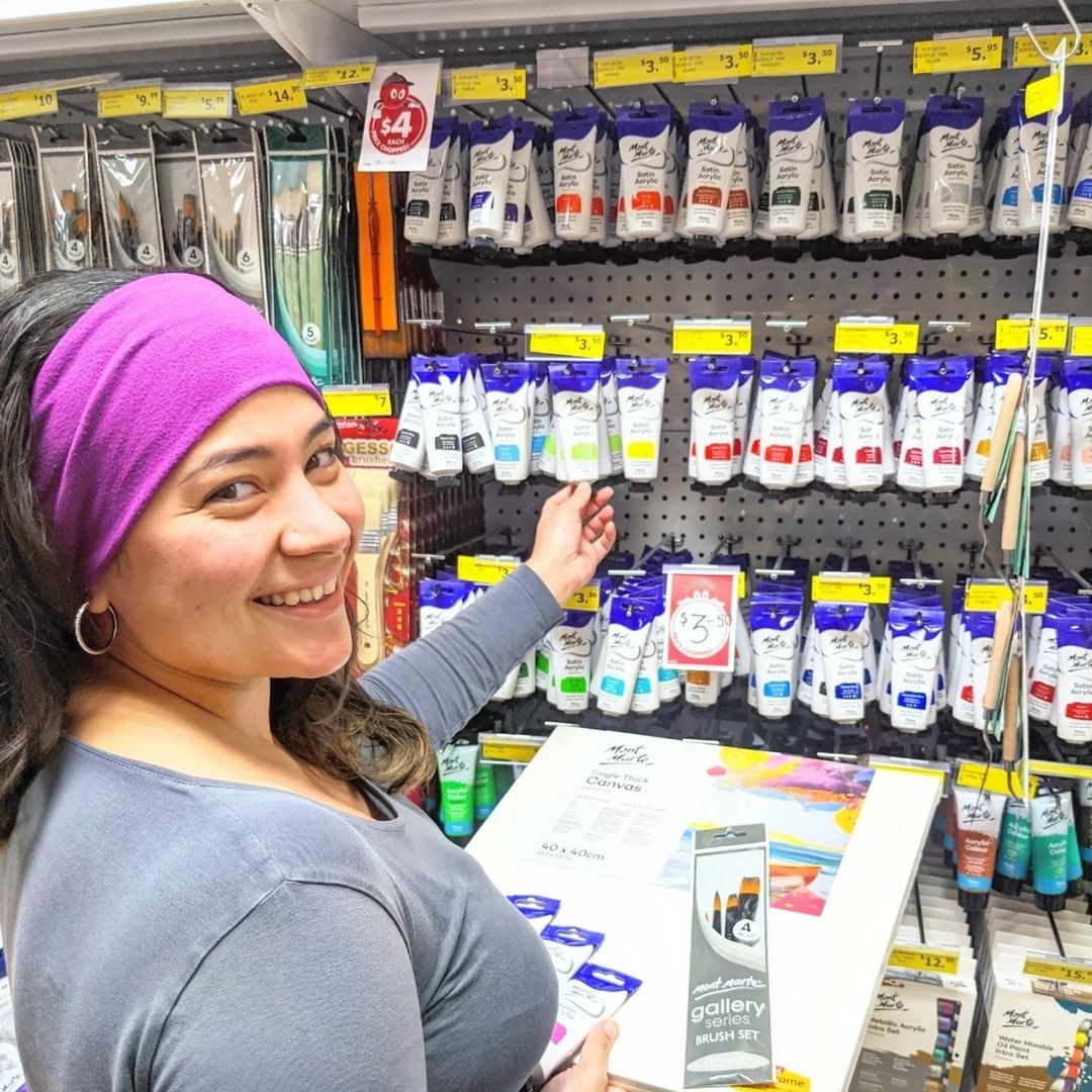 1. Person shopping and smiling holding Mont Marte products in a shop with various Mont Marte products.