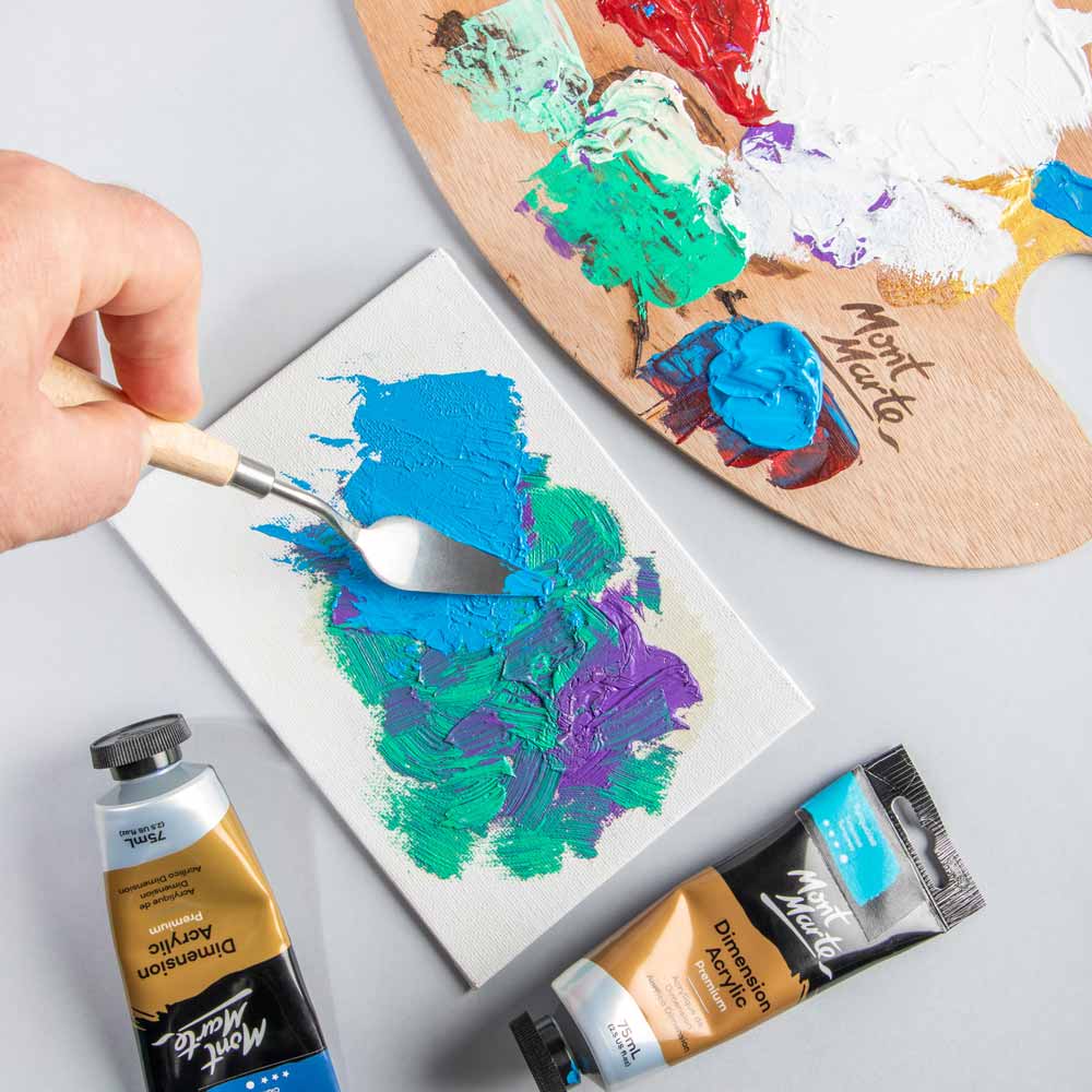 1. Palette knife mixing blue, green, and purple paint near a wood palette covered in paint