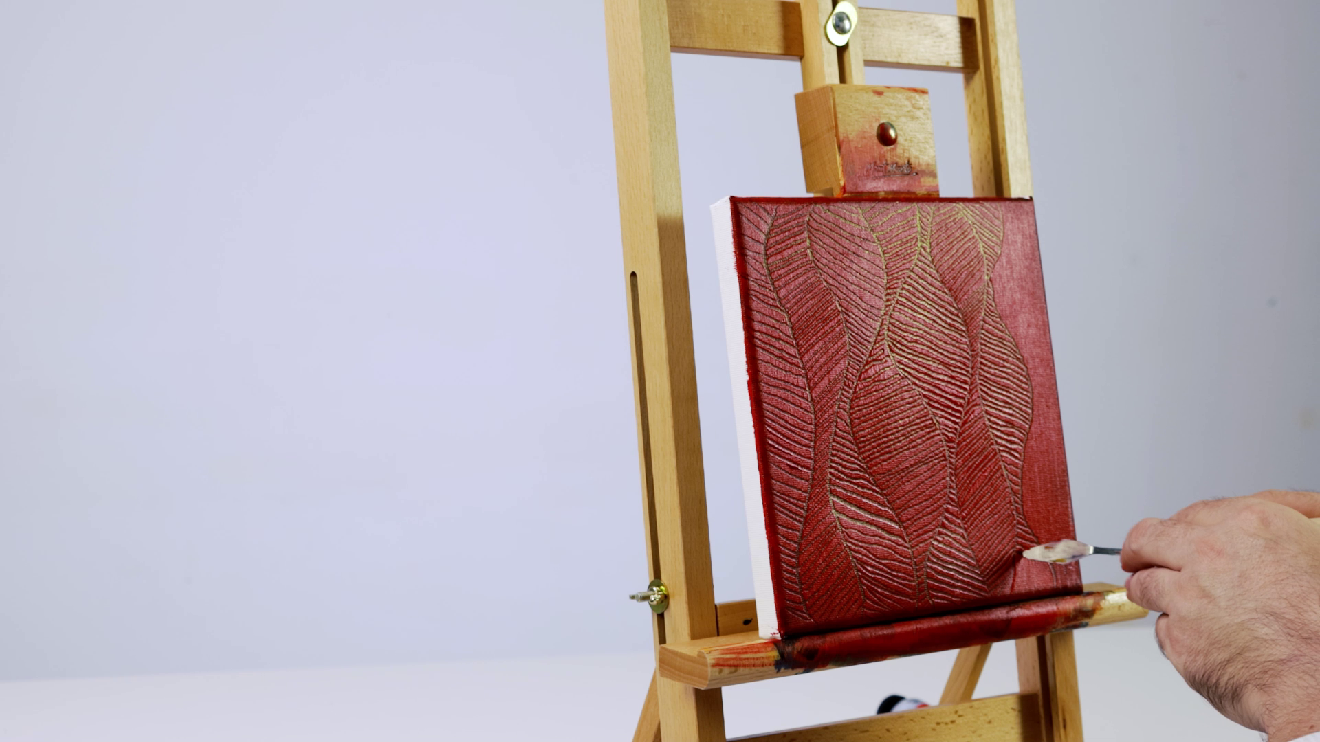 1. Sgraffito technique being done with a palette knife on a red oil painted canvas