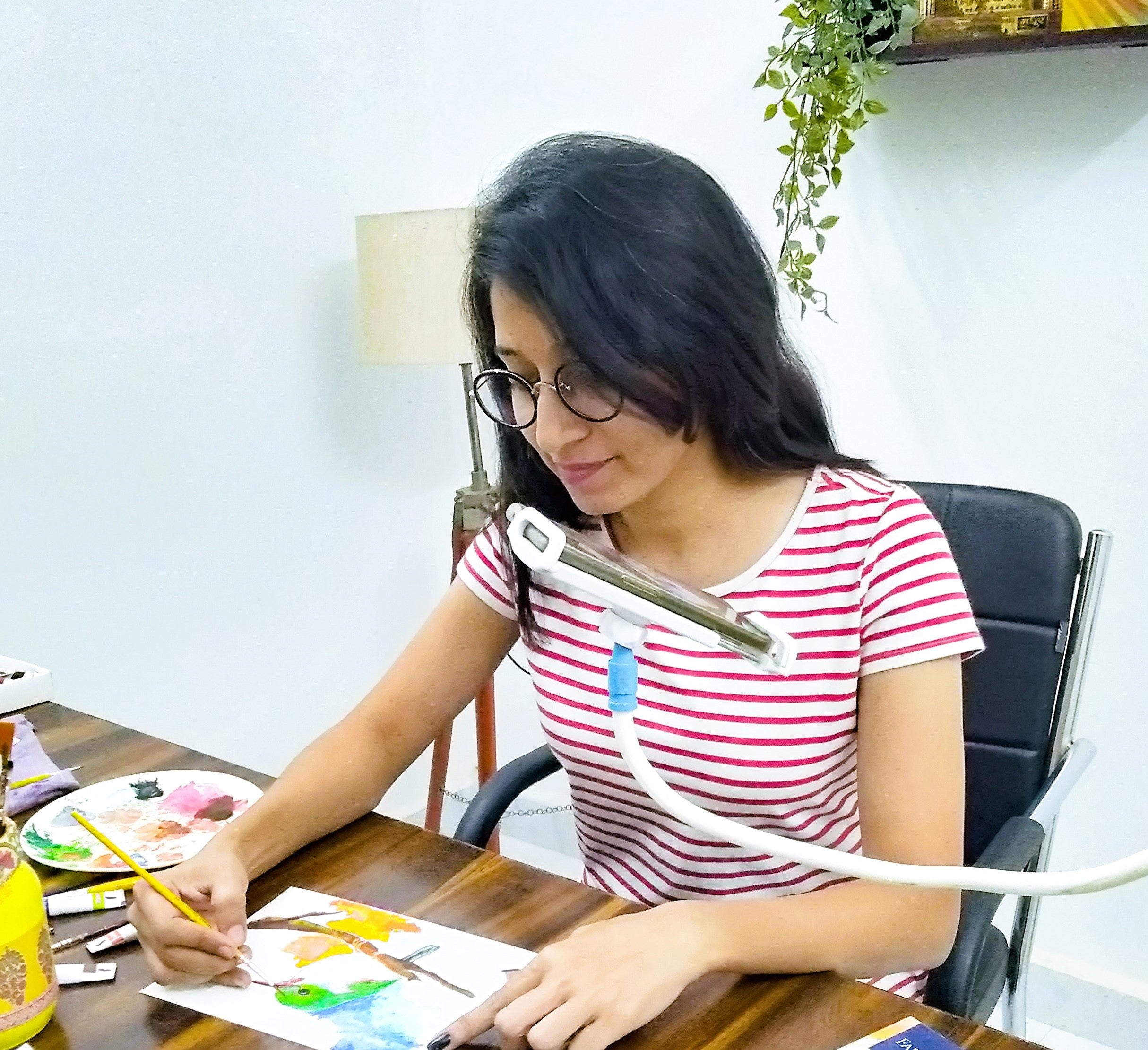 1. Sonam working on an artwork at a wooden desk with her phone recording the process