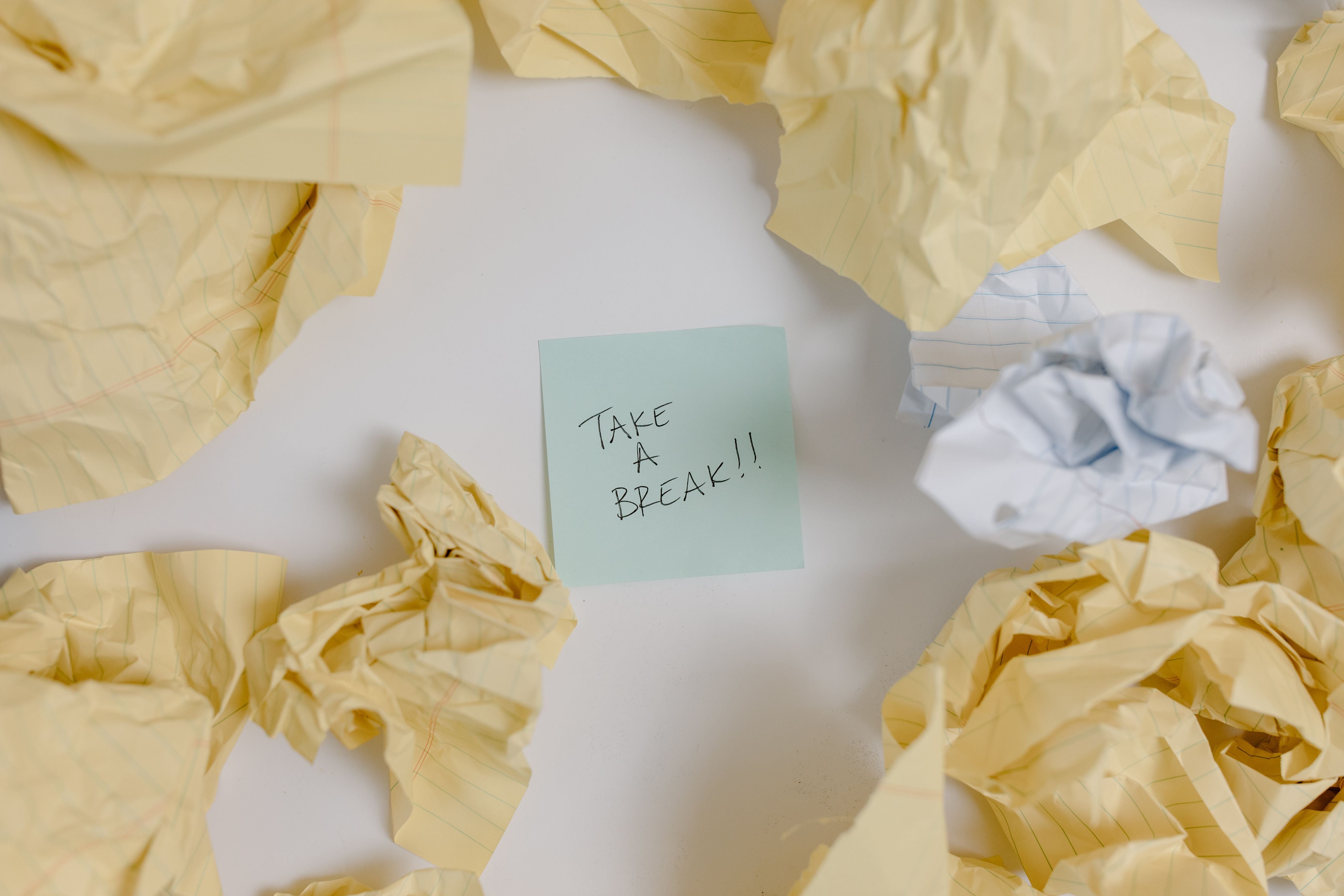 1. Sticky note reading 'take a break' on a white surface surrounded by crumpled paper