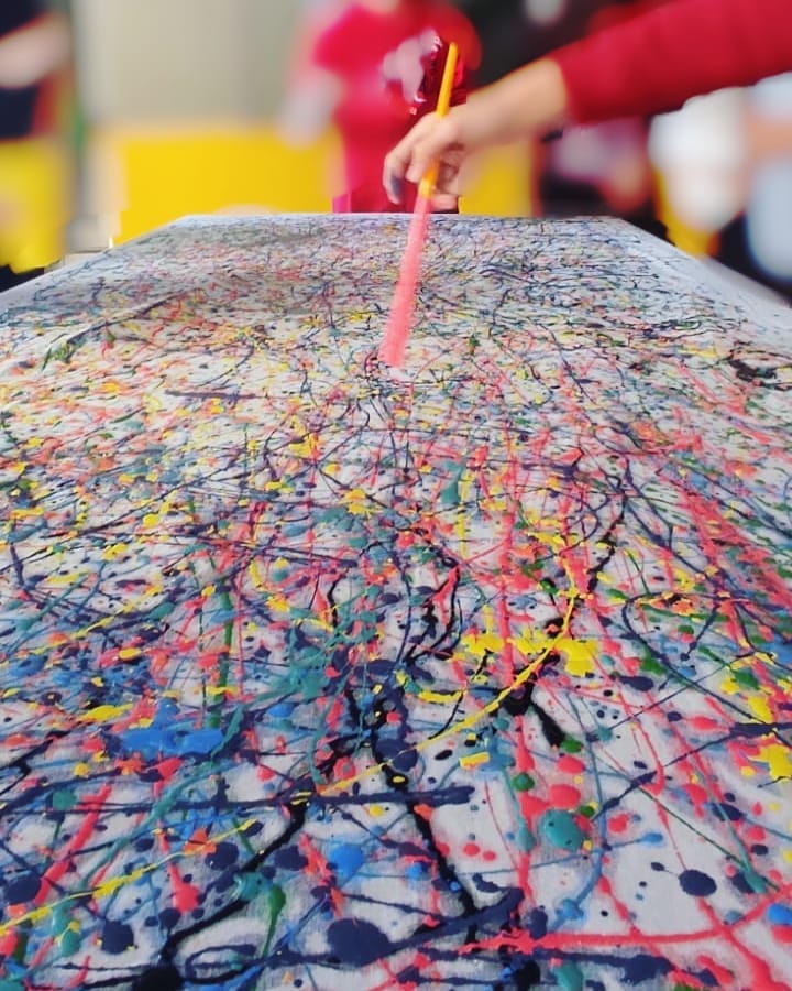 1. @carlabonini.arte rainbow coloured action painting with lines and dots of splattered paint on a white surface