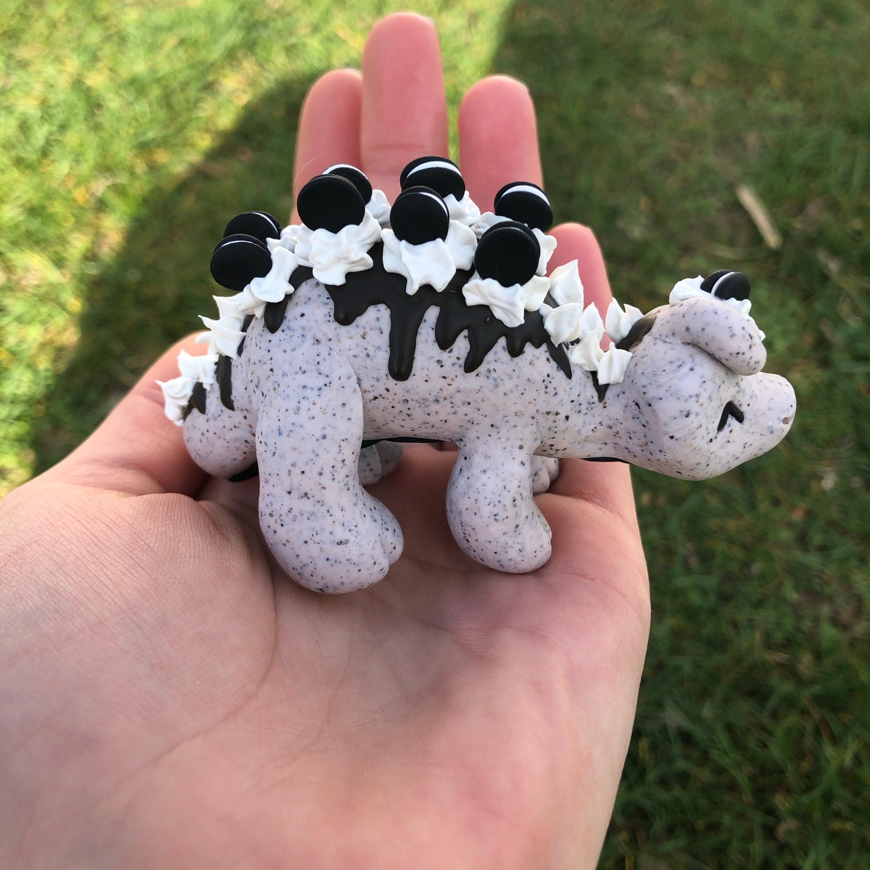 1. @kyliesmenagerie polymer clay cookies and cream themed dinosaur sitting on a hand