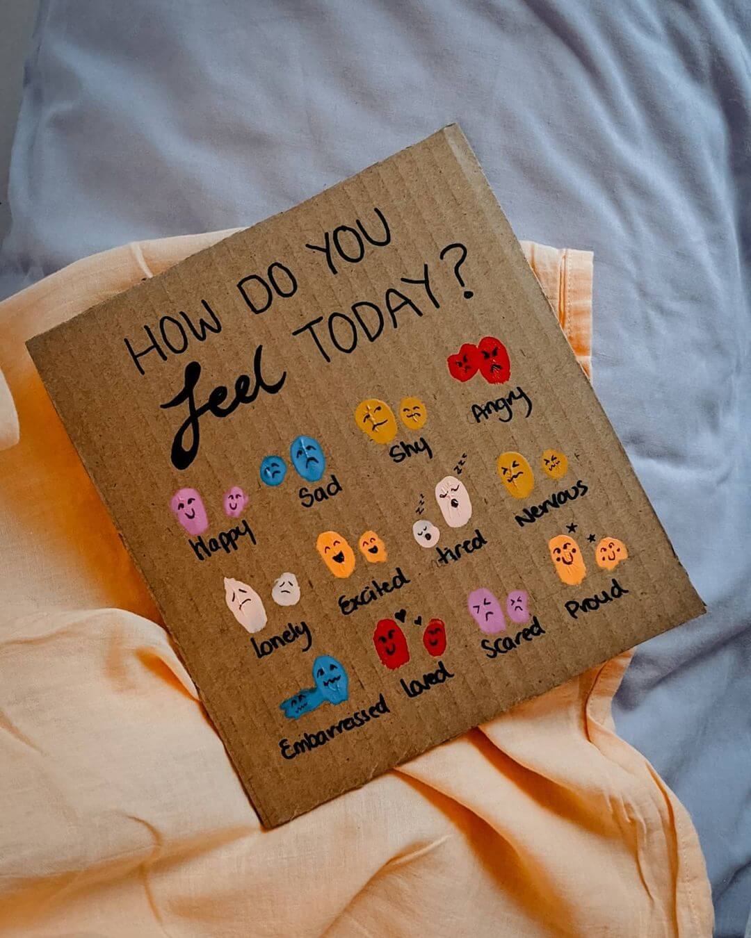 A piece of cardboard with a feelings chart drawn on with twelve colours and cartoon faces to show the emotions.