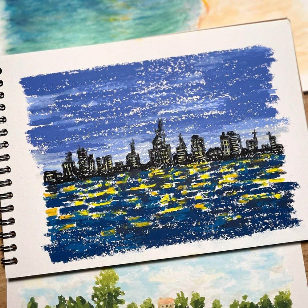 Bright blue cityscape at night drawn on a sketch book with a large tooth paper.