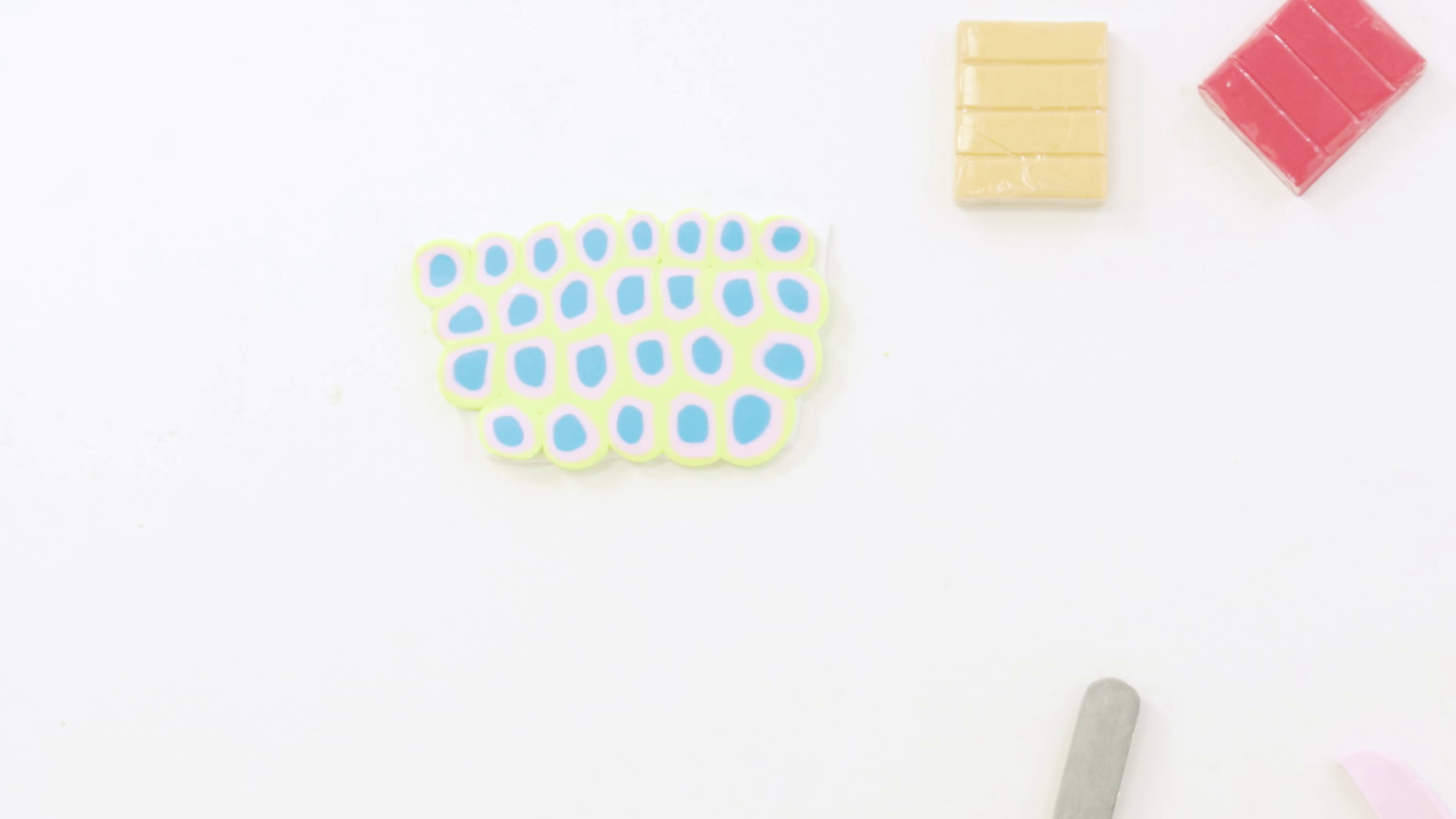 10. Circular polymer clay pattern using green, blue, and pink colours