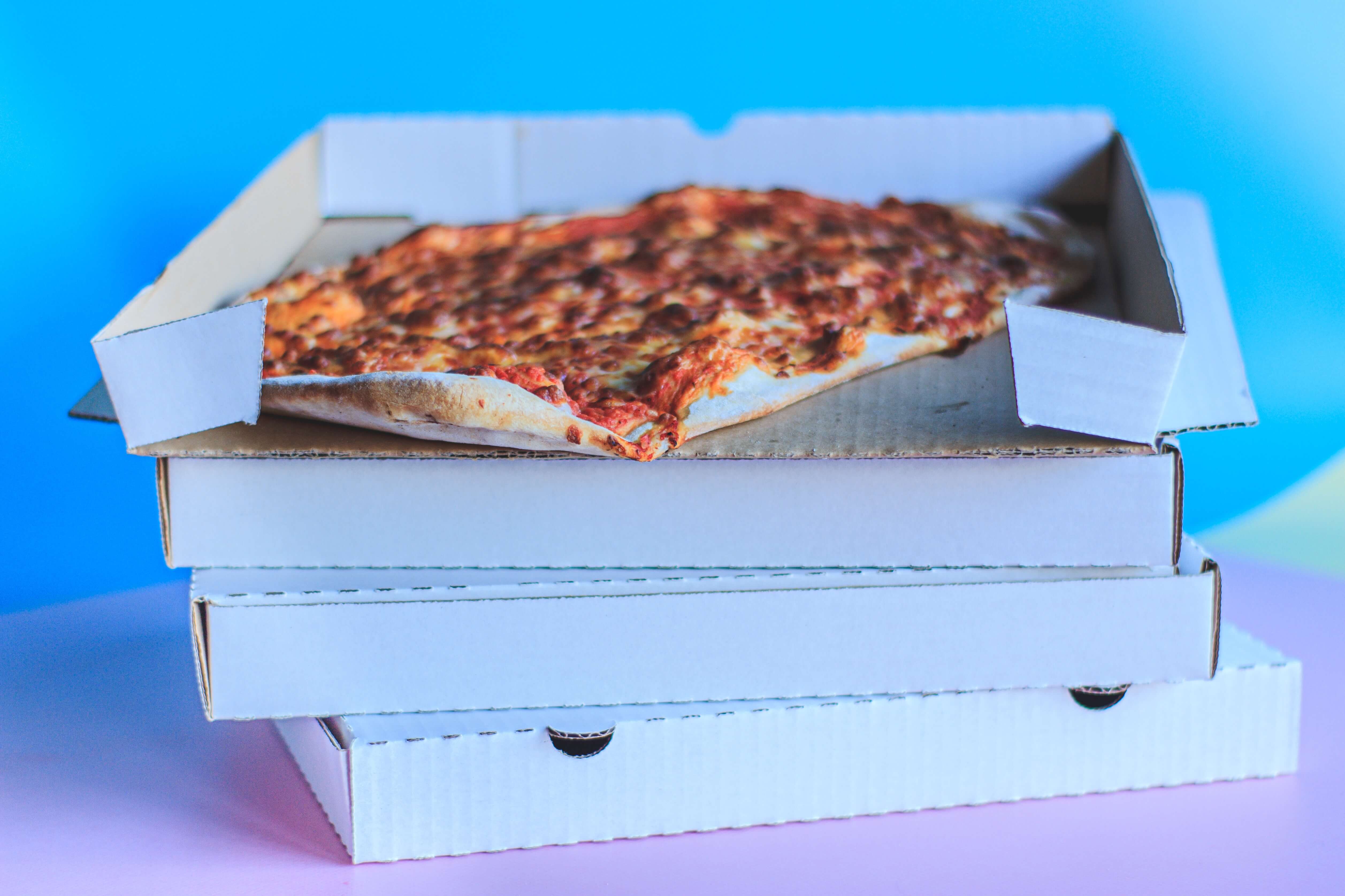 Four pizza boxes stacked on top of each other with an open box on top.