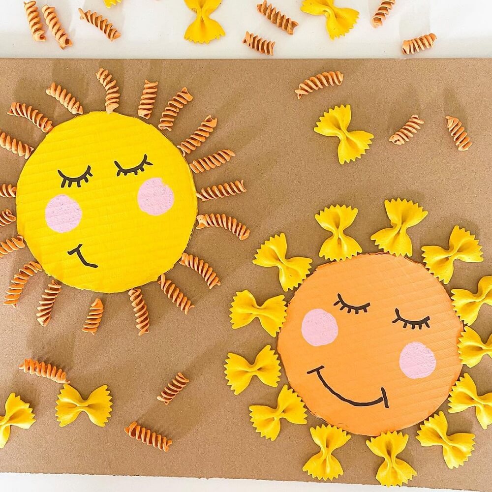 Two smiling sun faces made from cardboard and pasta.