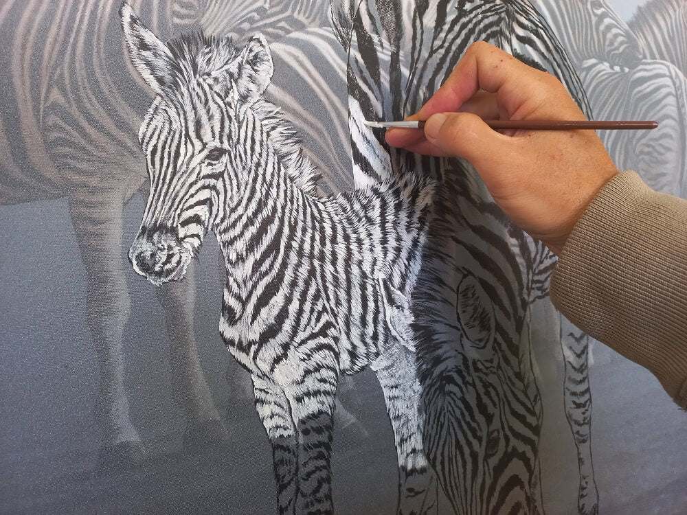Upclose progress shot of Dawie's hand painting a zebra with titanium white acrylic paint.