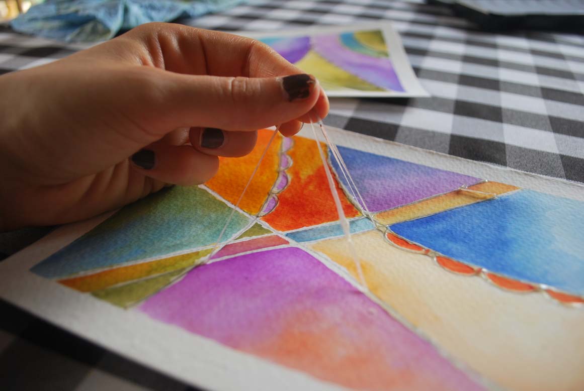 Hand peeling off masking fluid from water colour paining. 