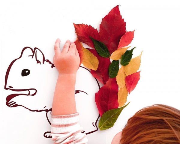 A squirrel made from leaves, glued to a white sheet of paper.