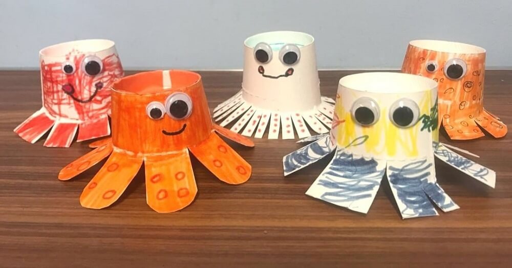 Five coloured octopus made from paper cups with googly eyes.