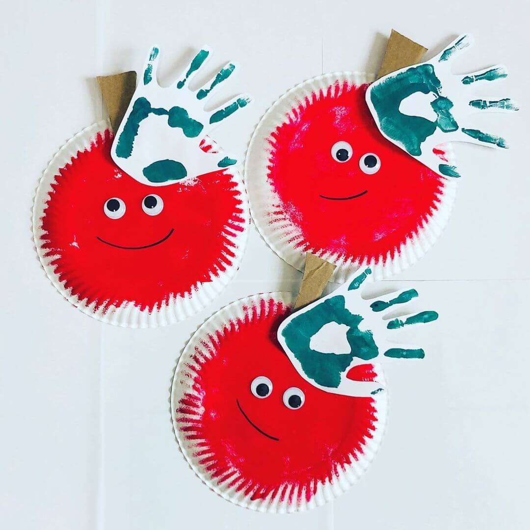 Three apples made from paper plates and handprints with green and red paint