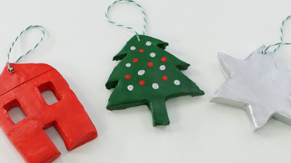 Three Christmas tree ornaments red house, green tree and silver star.