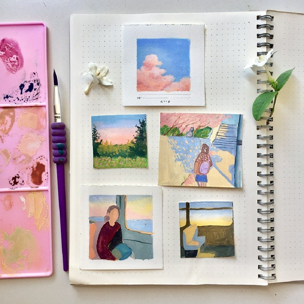 Four small gouache paintings laying on a notebook of a sky, walk in the park and on the train.