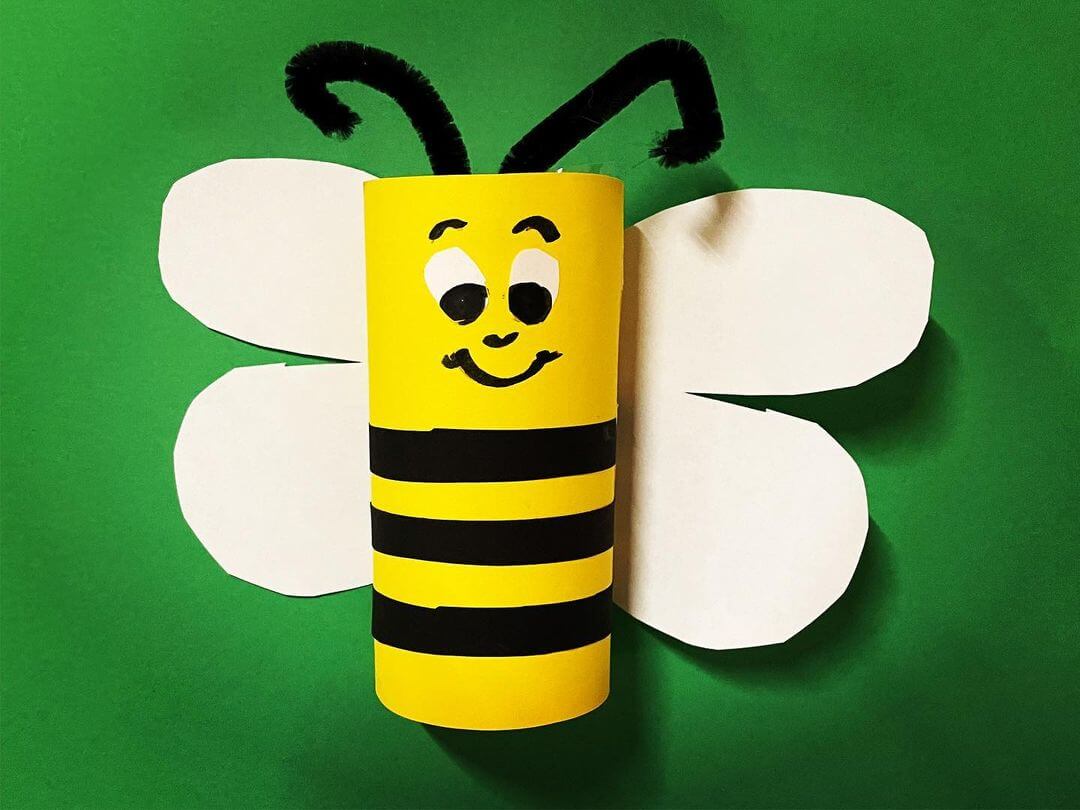 A brightly coloured toilet roll with paper wings and markers to look like a bumble bee.